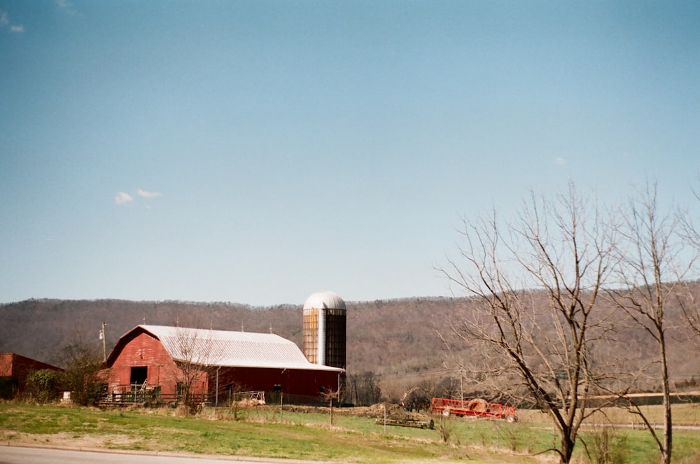 red and white barn house near bare trees under blue sky during daytime