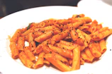A vibrant shot of tomato basil penne pasta in a sleek black box with golden accents.