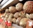 A display of cured meats wrapped in netting and stacked neatly on a shelf, with some price tags attached.