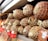 A display of cured meats wrapped in netting and stacked neatly on a shelf, with some price tags attached.