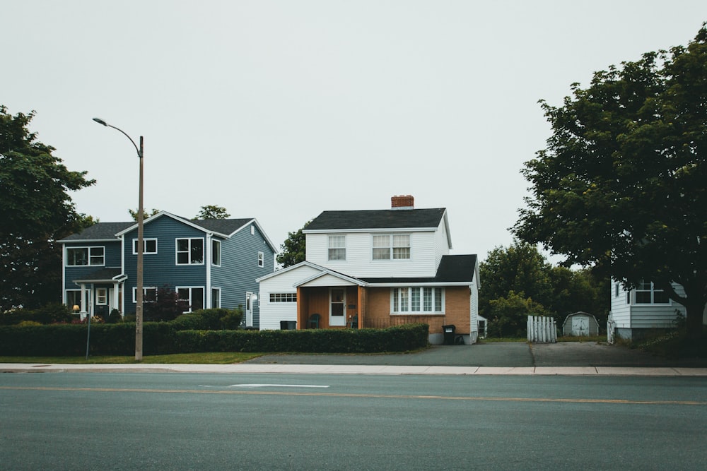 white and brown house beside green trees under white sky during daytime