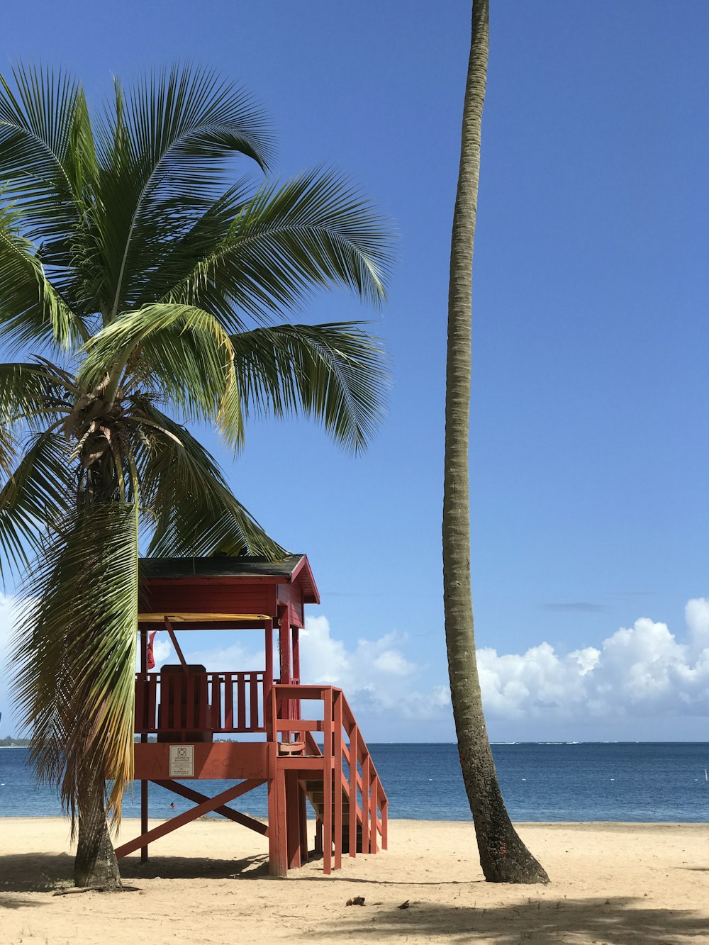 red wooden lifeguard tower near body of water during daytime