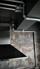 Close-up of a stainless steel exhaust hood with ducting in a commercial kitchen.