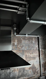 Close-up of a stainless steel exhaust hood with ducting in a commercial kitchen.