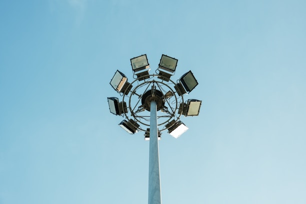 Close-up of a sleek AC solar flood light mounted on a tall pole illuminating a parking area.