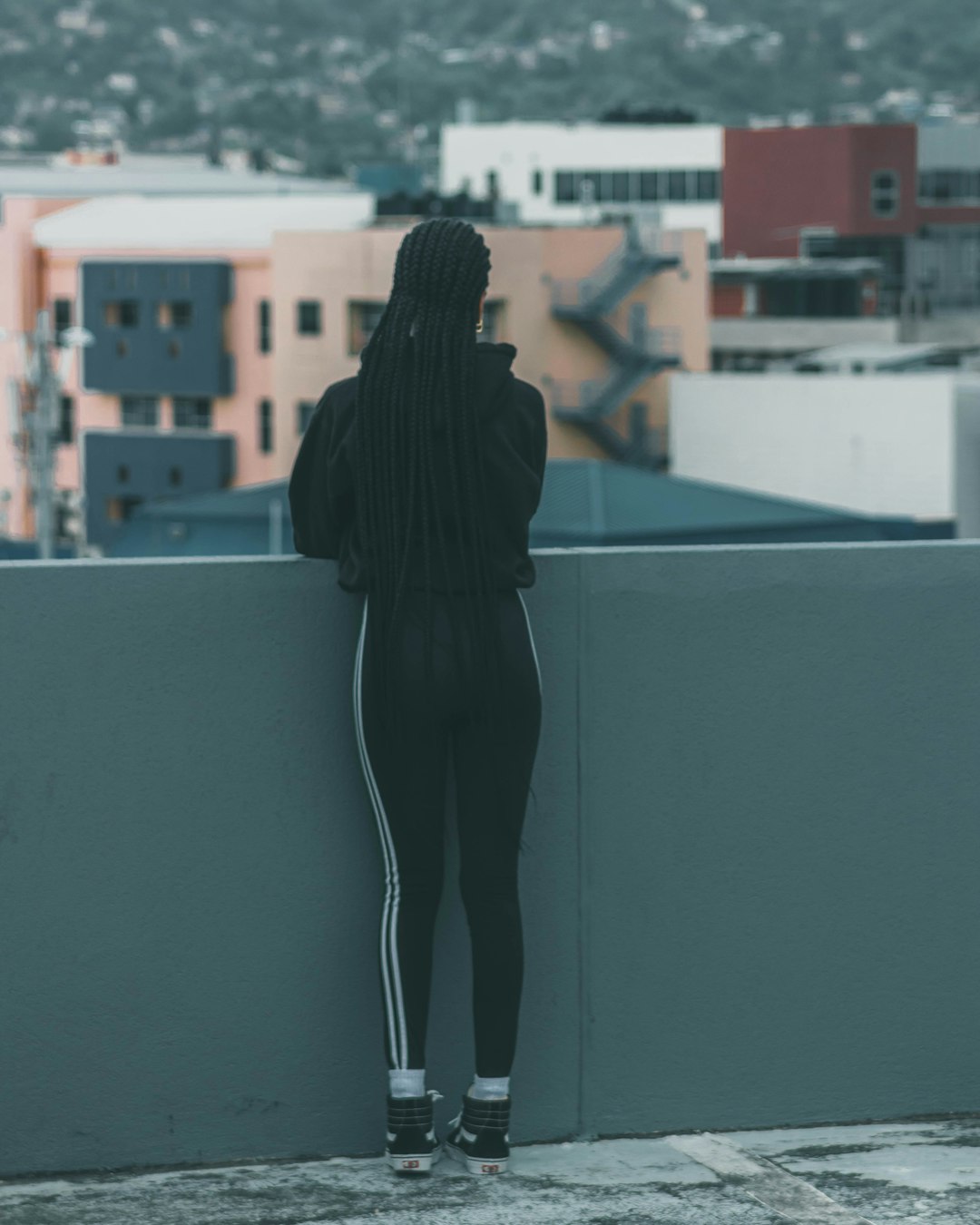 woman in black long sleeve shirt and black pants standing on gray concrete wall during daytime