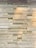 A wall displaying various wooden plaques with engraved names and messages, likely representing donors or memorials. The plaques are arranged in a brick-like pattern, with each one varying slightly in wood tone and text size.