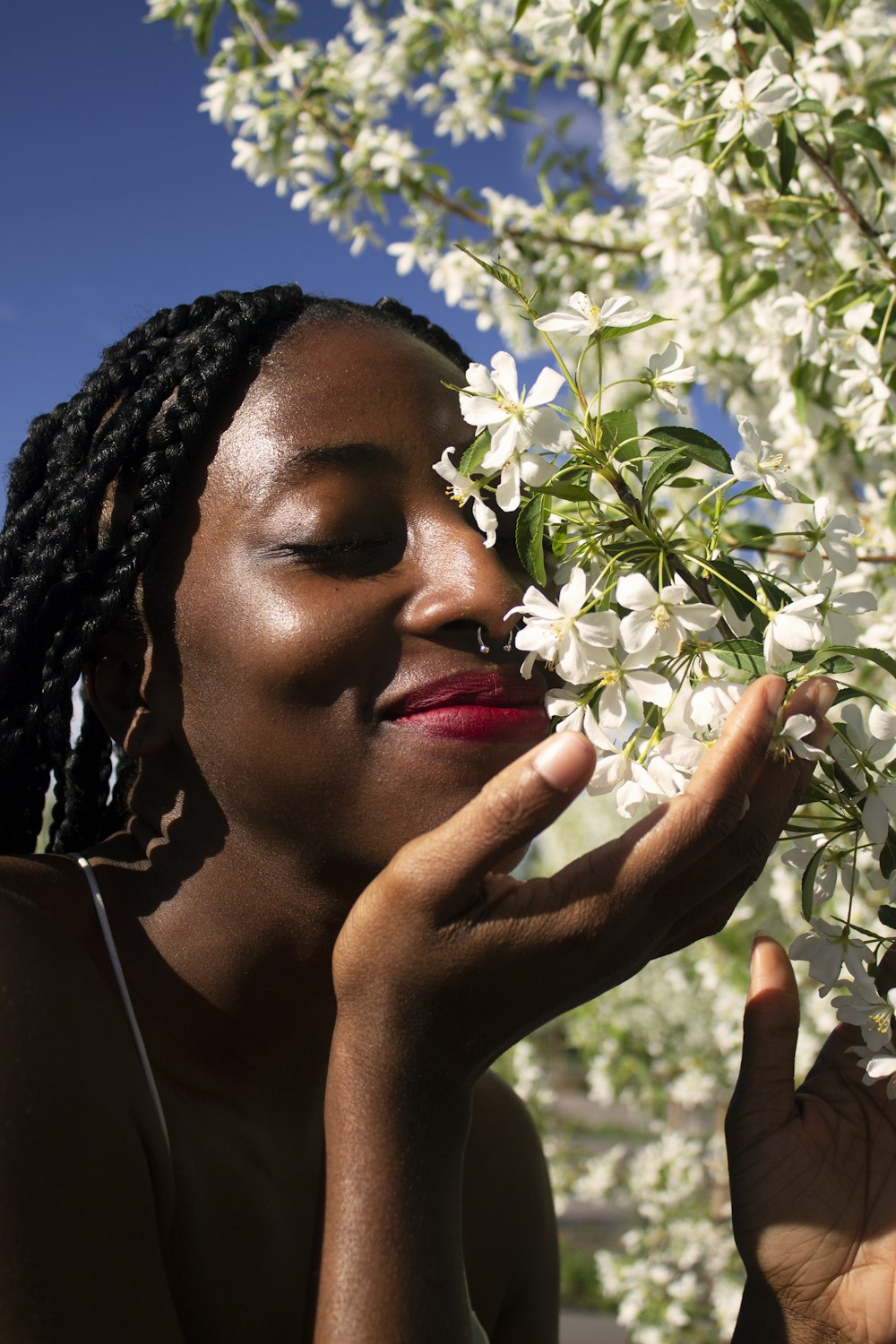 woman in black and white floral head dress holding white flower