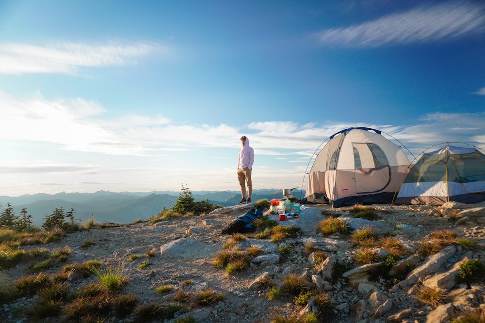 man in white t-shirt standing near white dome tent during daytime