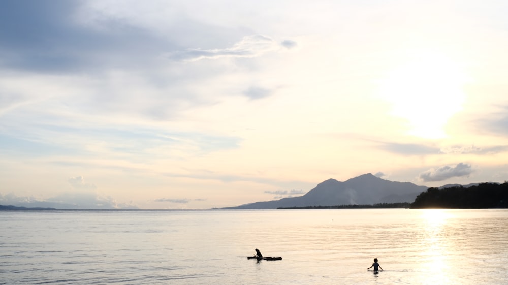 silhouette of 2 people on body of water during daytime