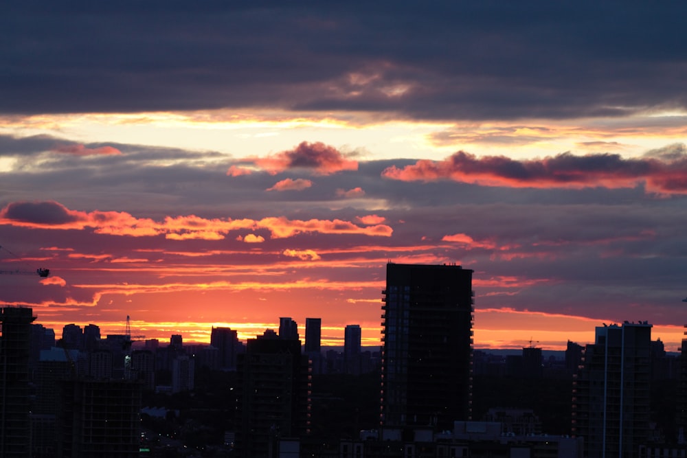 city skyline under orange and gray cloudy sky during sunset