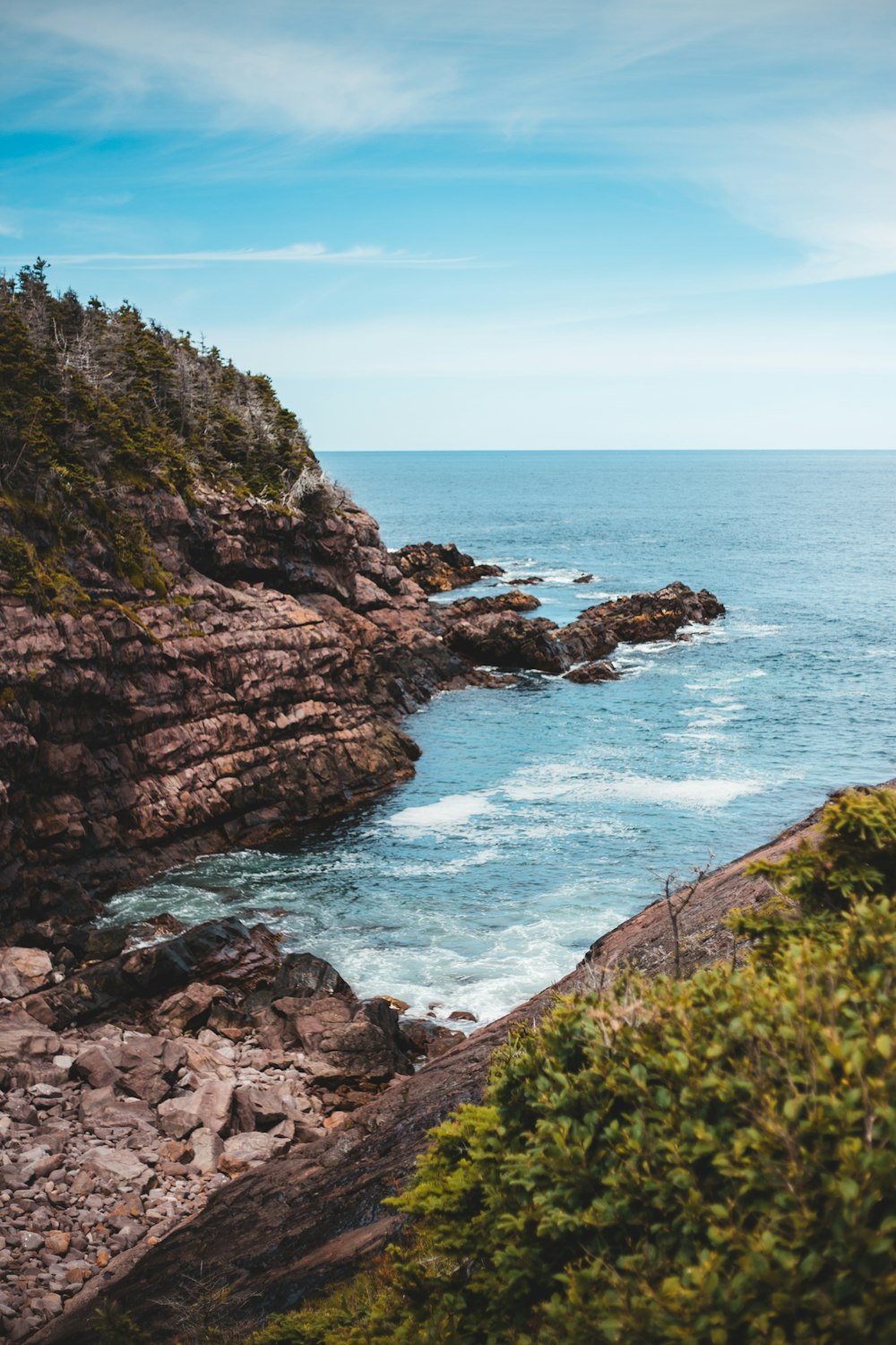 green and brown mountain beside sea during daytime