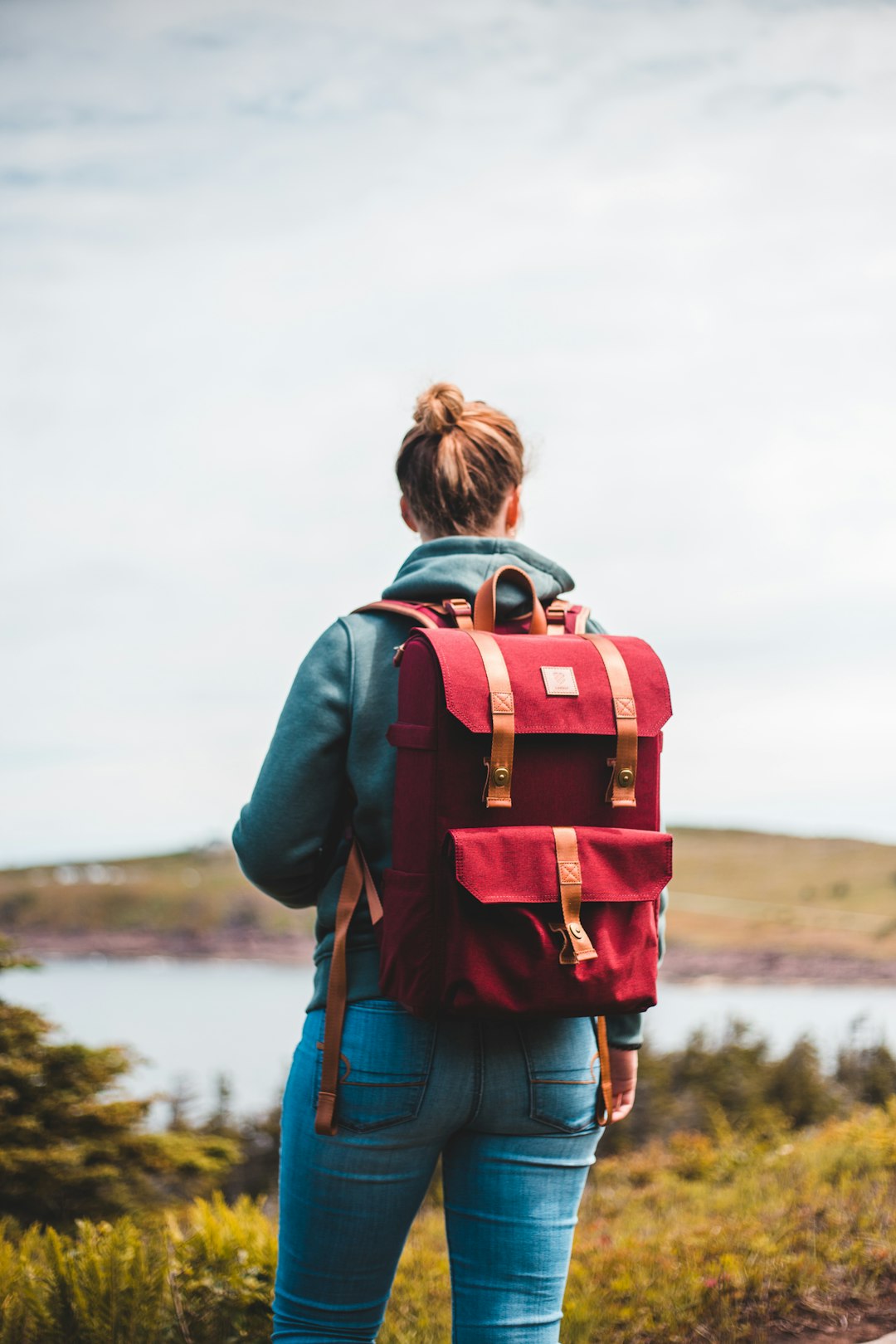 woman in blue denim jacket with red and black backpack