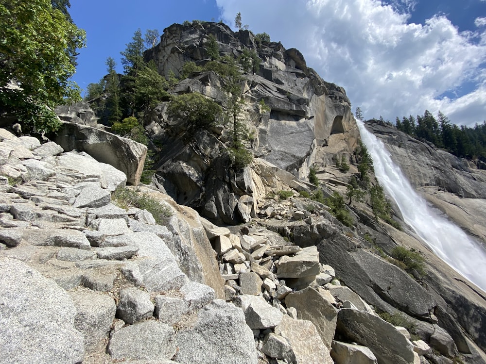 brown rocky mountain with waterfalls under blue sky during daytime