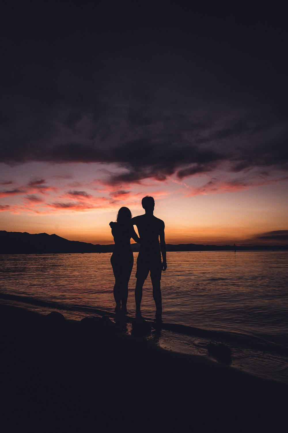 silhouette of man and woman kissing on beach during sunset