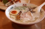 An elegant bowl of steaming ramen topped with soft-boiled egg and sliced pork.