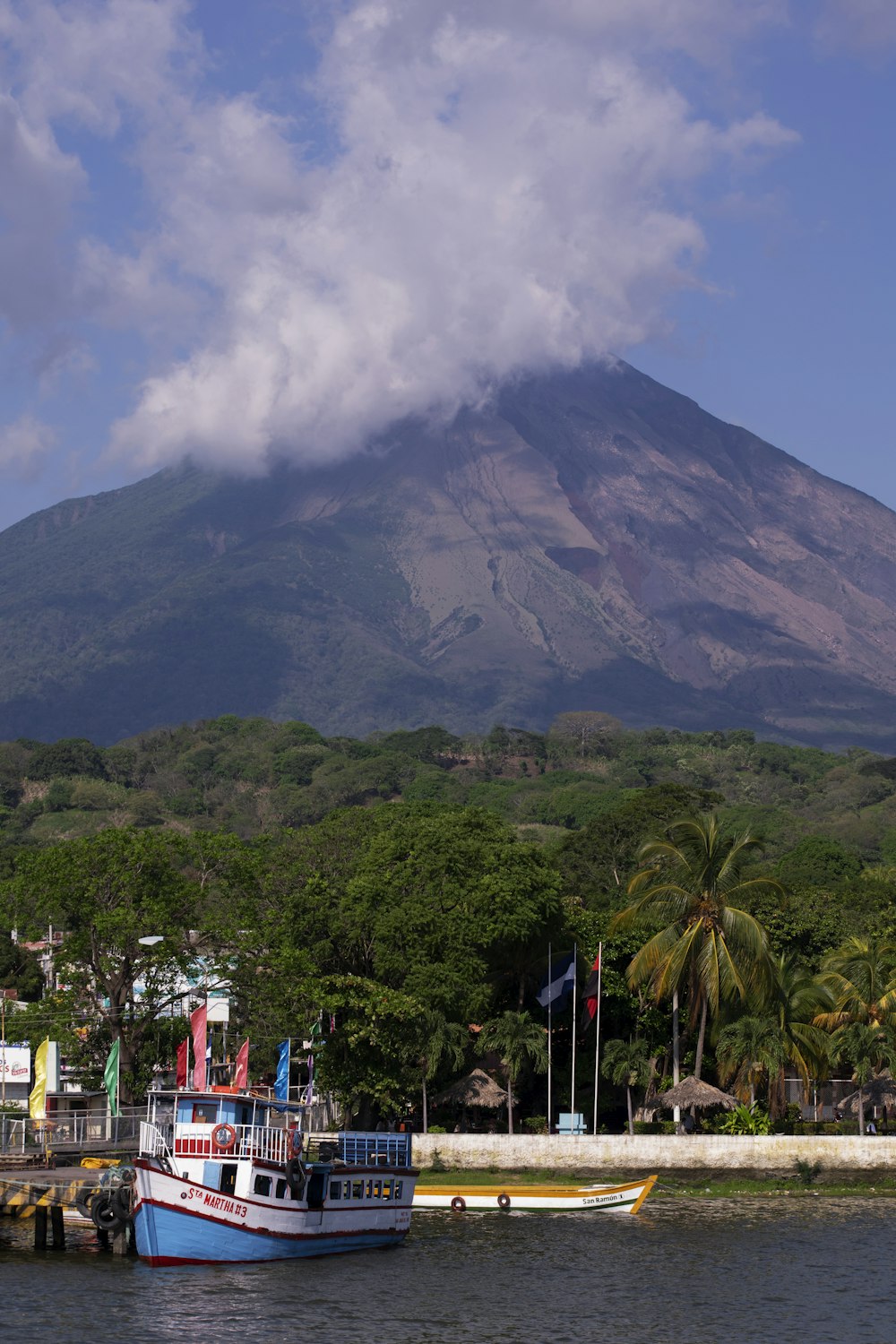 people walking on street near green mountain under white clouds during daytime