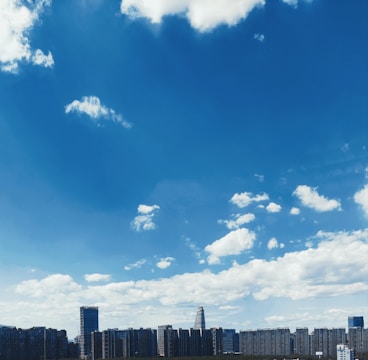 A modern city skyline featuring high-rise residential and commercial buildings under clear skies.