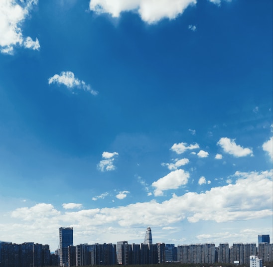 A modern city skyline with various buildings under a clear blue sky.
