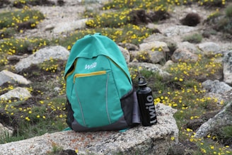 green and black backpack on rocky ground