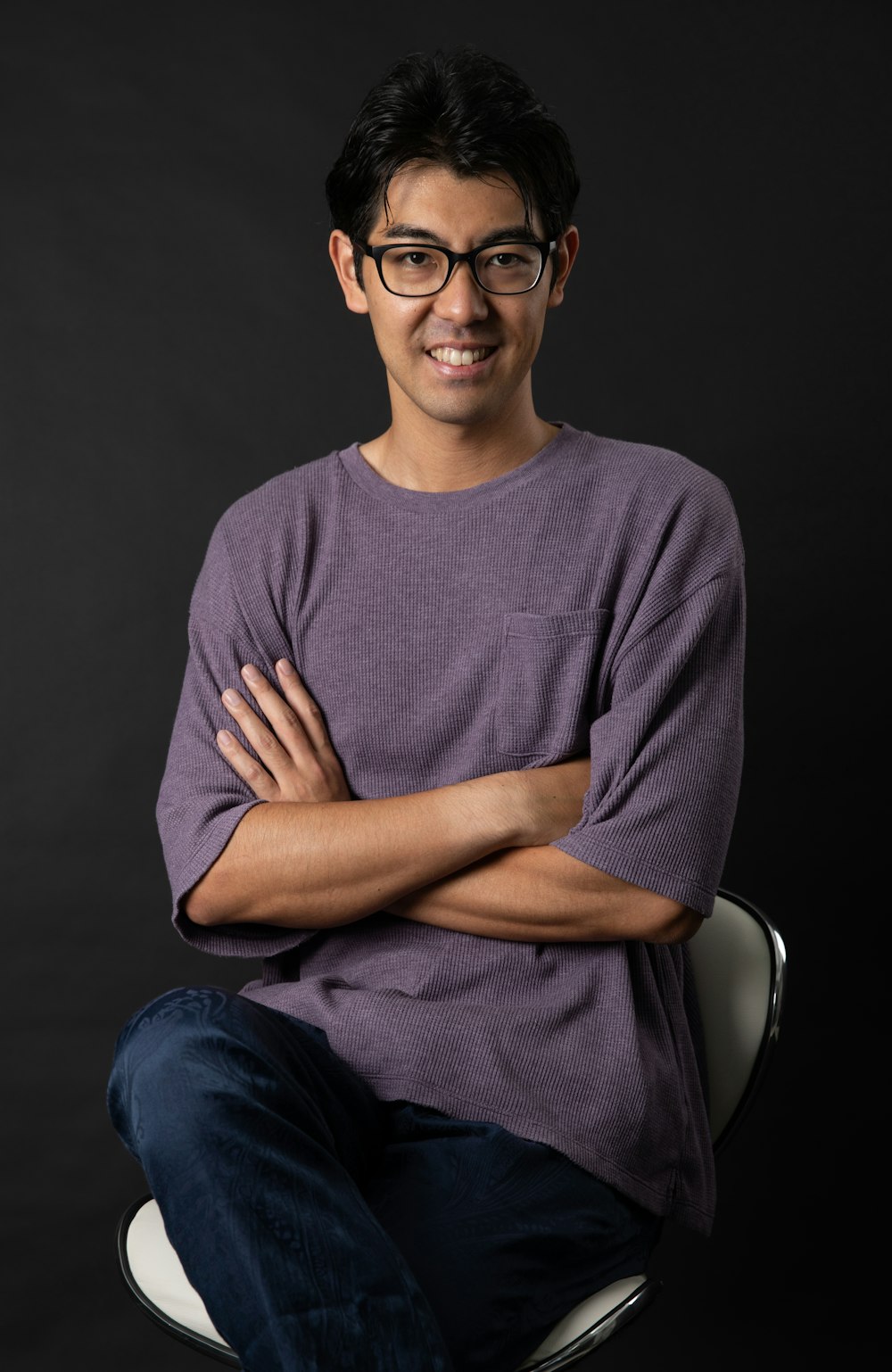 man in gray crew neck shirt and blue denim jeans sitting on black chair