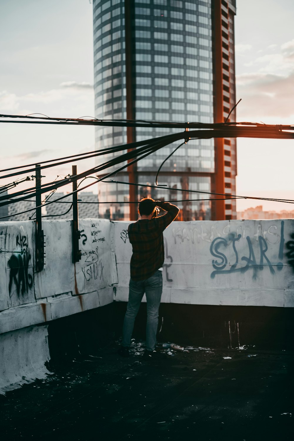 man in yellow hoodie and blue denim jeans standing on concrete wall during daytime