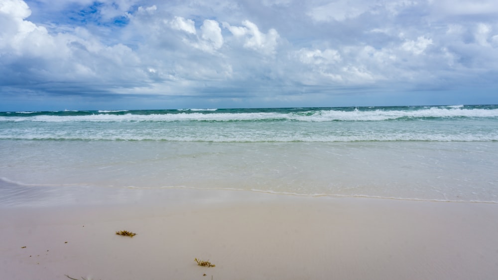 mar azul sob céu azul e nuvens brancas durante o dia