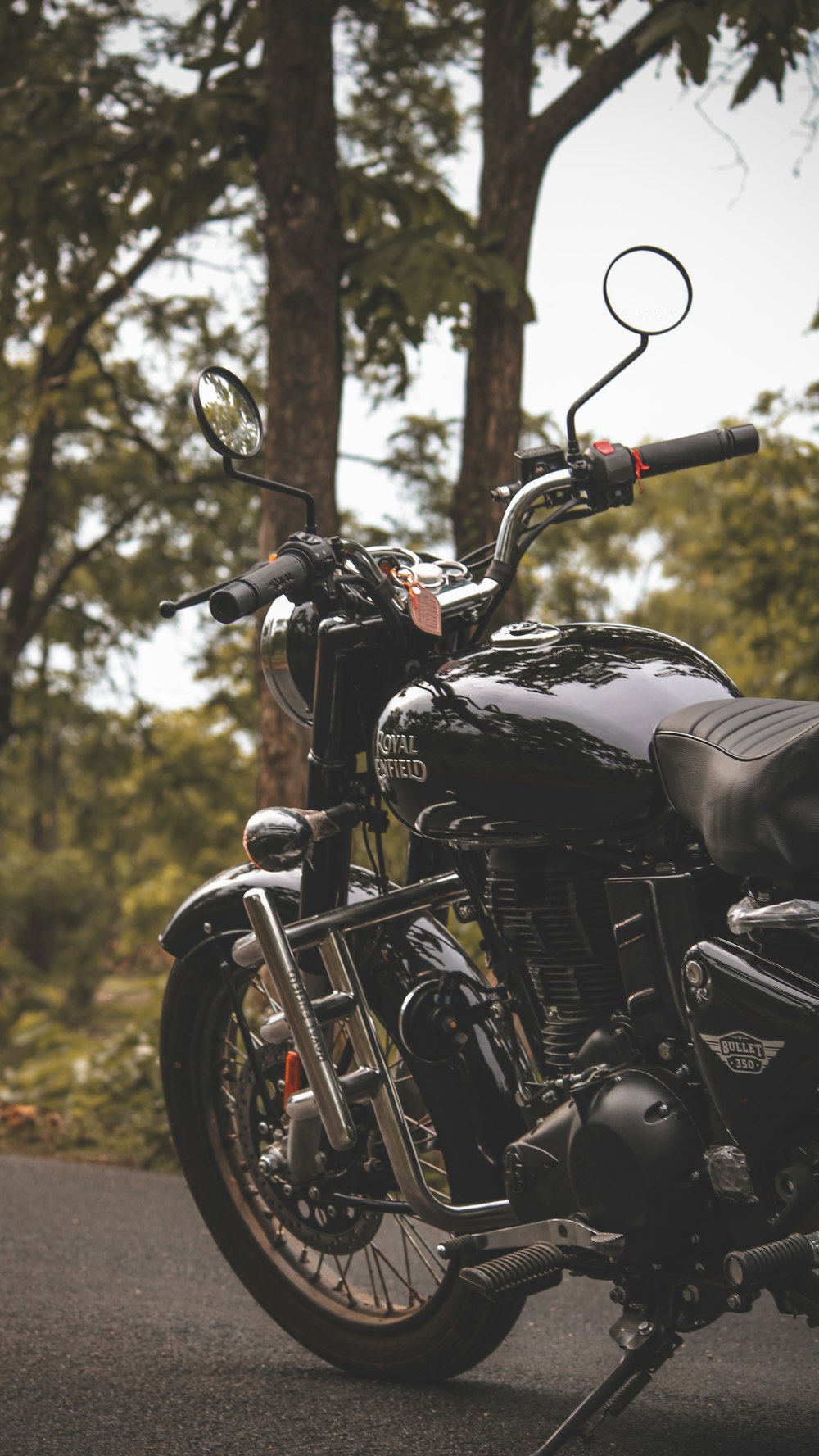 Motocicleta negra estacionada cerca de árboles durante el día