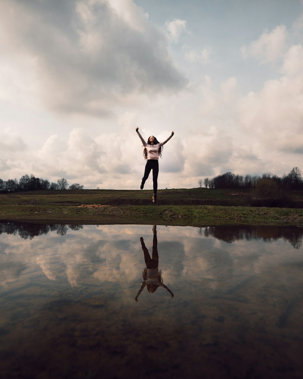 person standing on grass field near lake during daytime