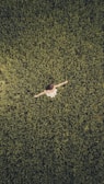 man in white shirt and black pants lying on green grass field