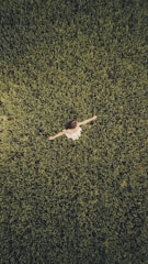 man in white shirt and black pants lying on green grass field