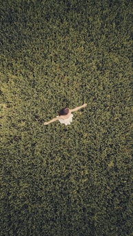man in white shirt and black pants lying on green grass field