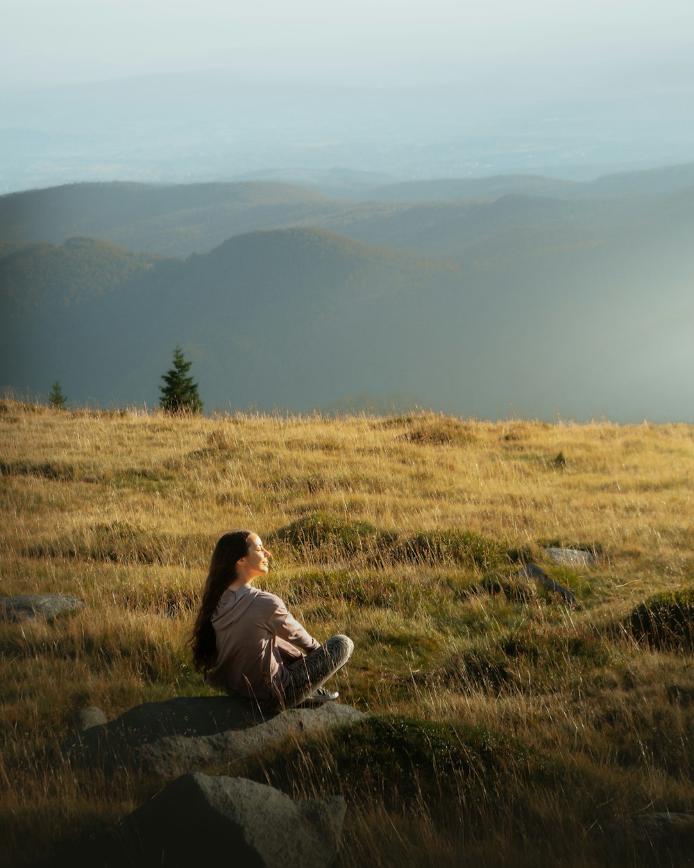 woman in red jacket sitting on green grass field during daytime