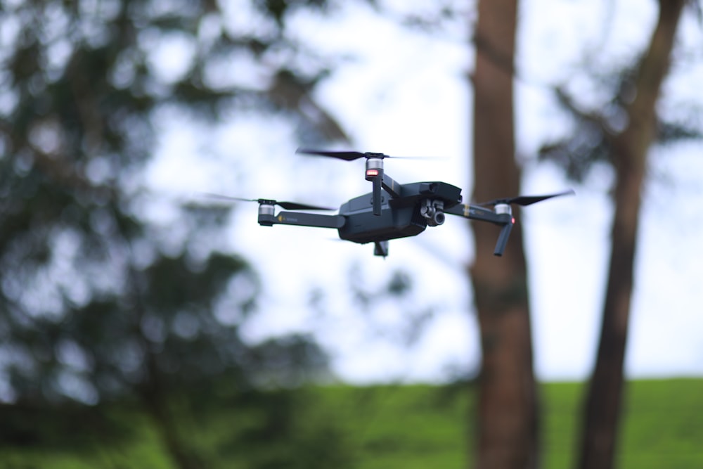 black drone flying in mid air during daytime