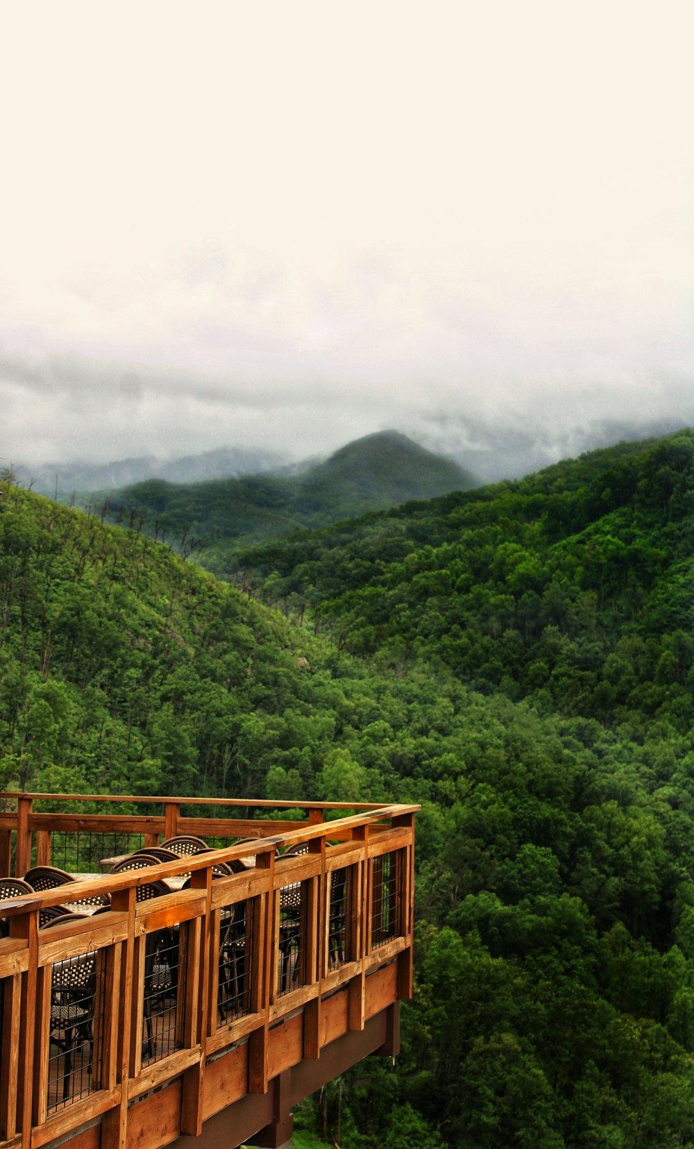 cerca de madeira marrom perto da montanha verde sob o céu branco durante o dia