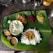 A traditional Indian meal served on a banana leaf, consisting of white rice topped with a lentil-based curry. Accompaniments include various vegetable dishes like beetroot and cabbage with lentils, a papadum, fried snacks, and a small dish of stew or curry. Salt is also placed directly on the leaf.