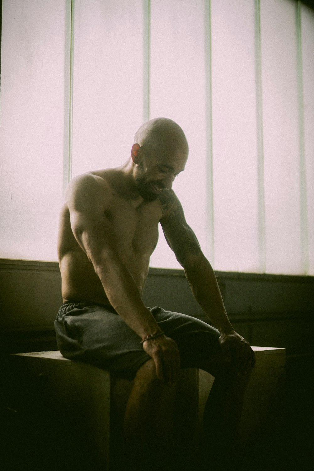 topless man in black denim jeans sitting on black wooden table