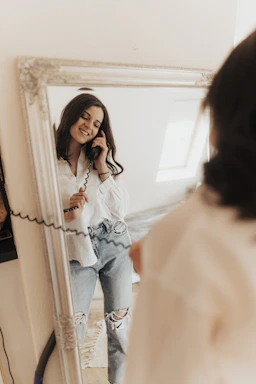 Imagen elegante de una mujer sonriente usando auriculares y hablando por teléfono en un ambiente moderno y femenino.