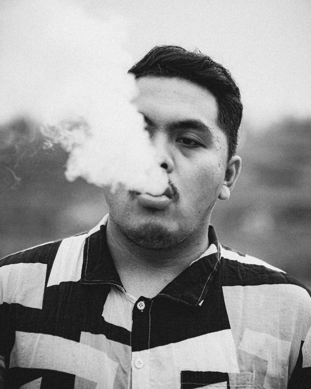 man in black and white striped polo shirt smoking