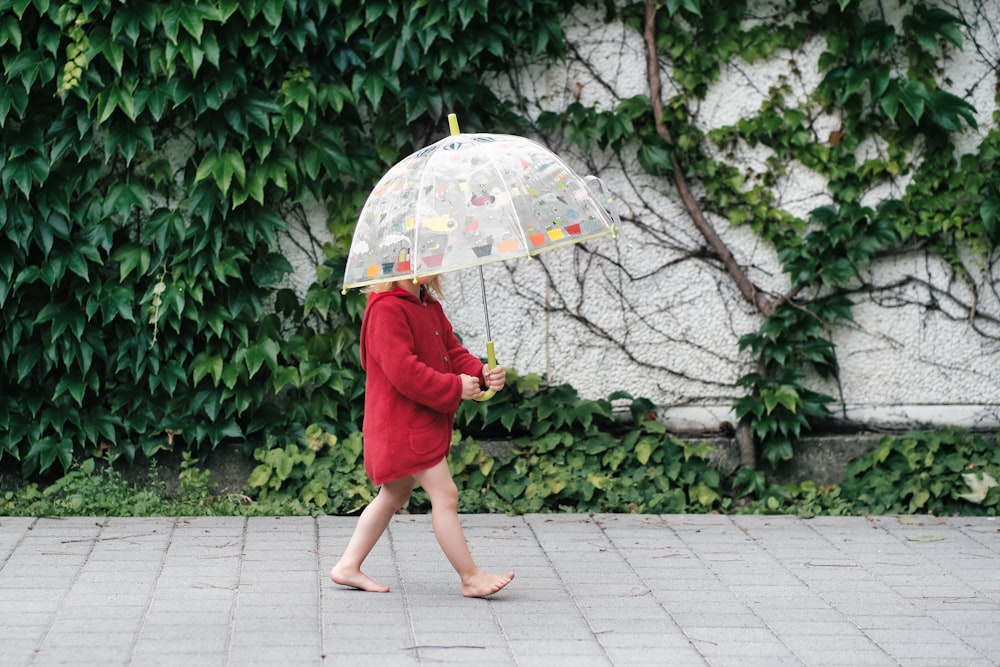 woman in red dress holding umbrella walking on pathway