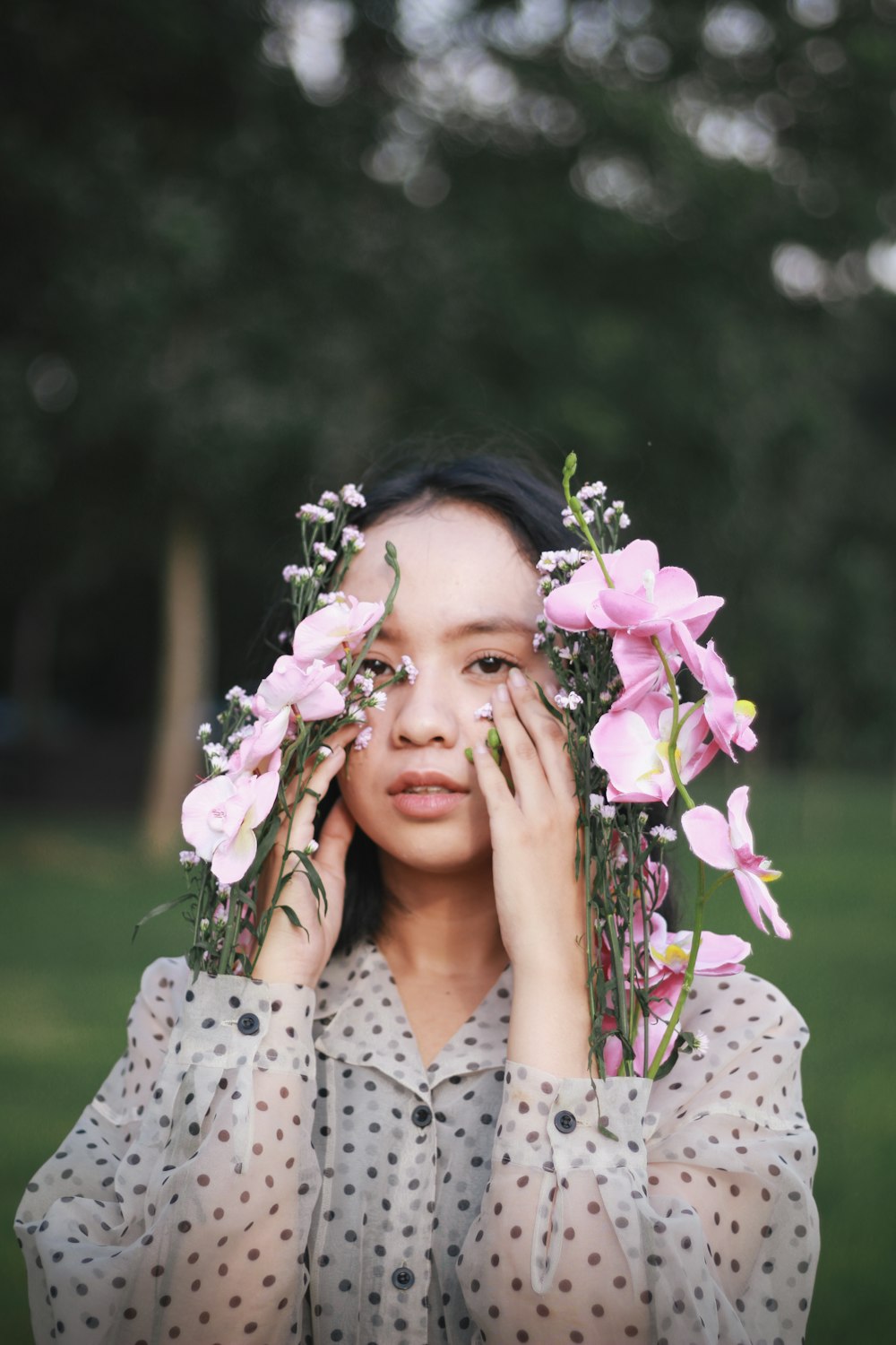 woman in white and black polka dot shirt holding purple flower