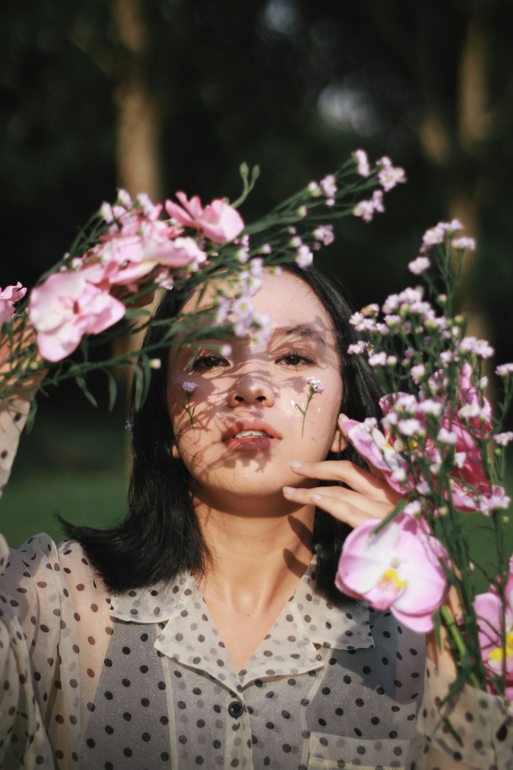 woman in white and black polka dot shirt lying on green grass field with pink flowers