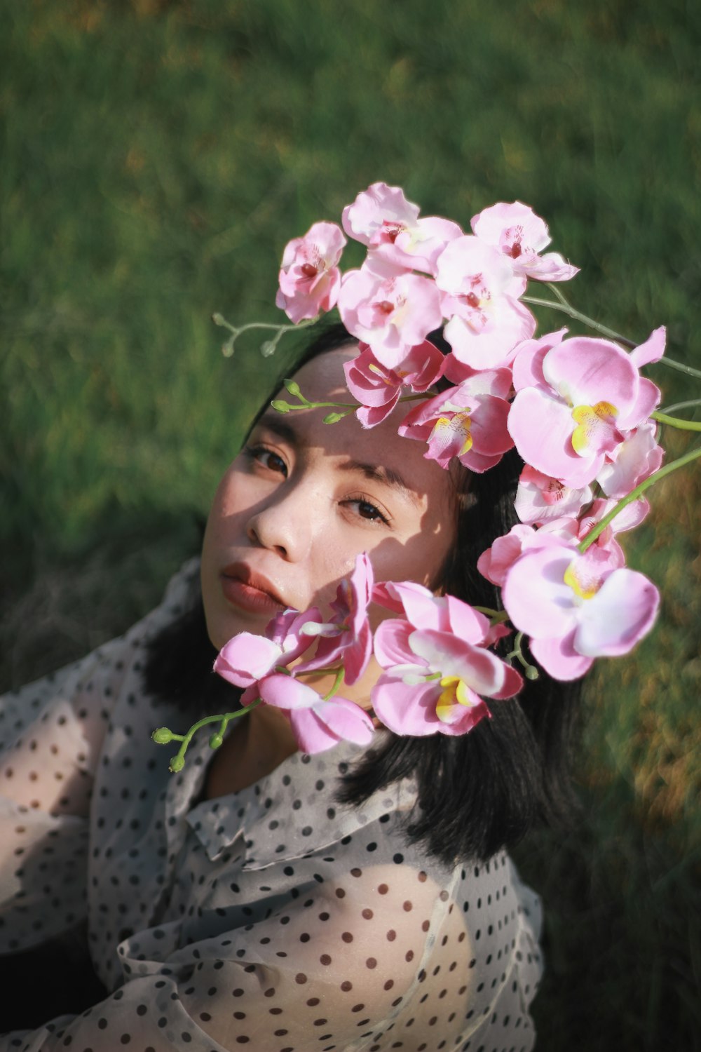 girl in white and black polka dot shirt with pink and white flower on head