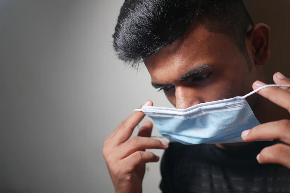 Person wearing a face mask, hands visible on either side of the mask
