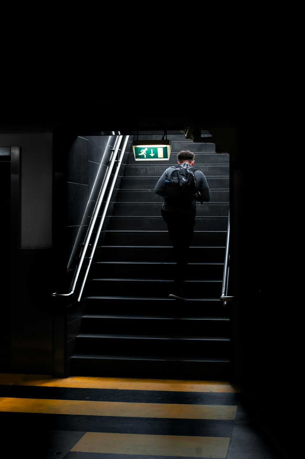 uomo in giacca nera che cammina sulle scale