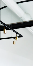 An industrial cage pendant light hanging above a minimalist dining table with matte black accents.