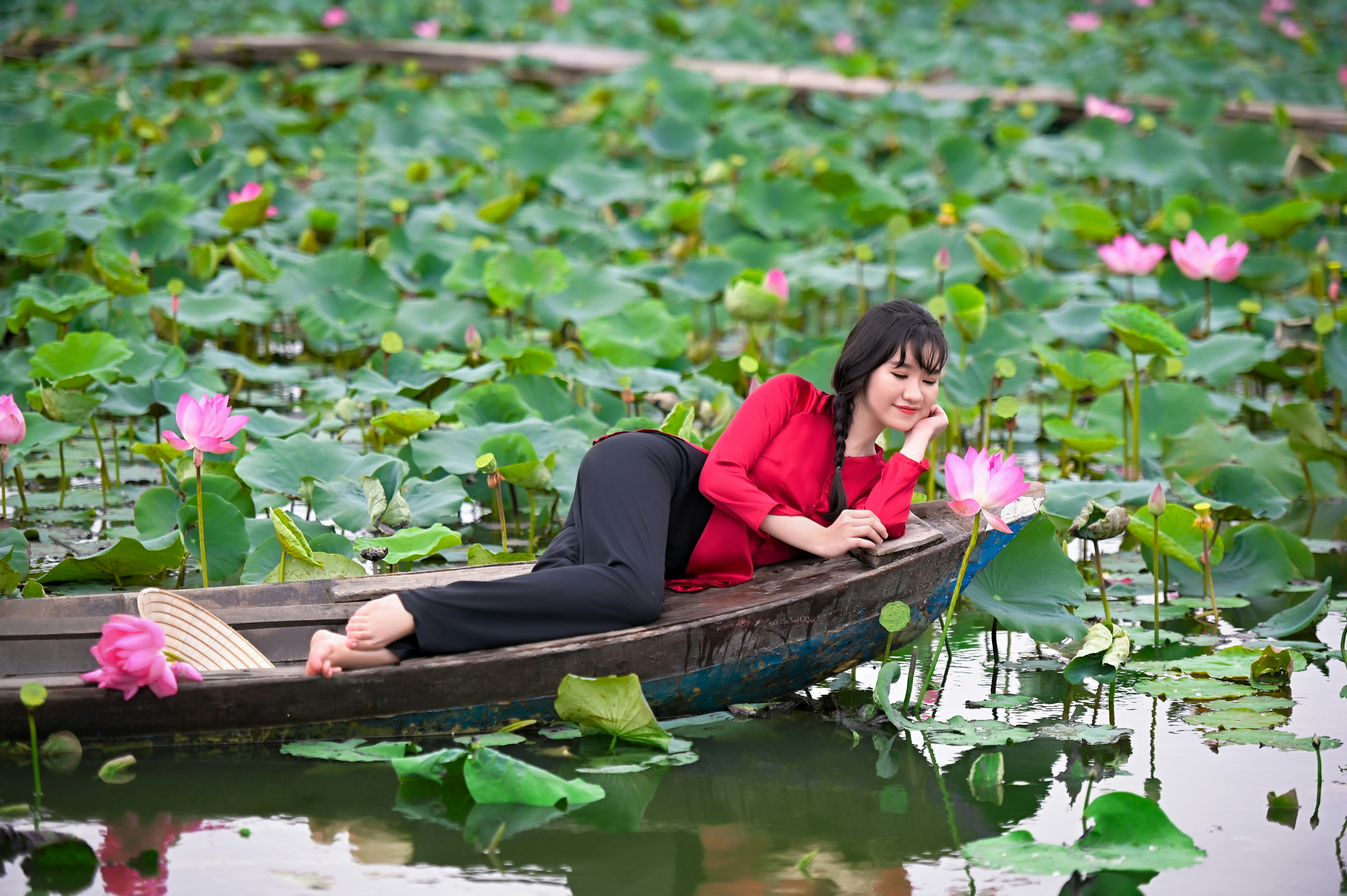 woman in red long sleeve shirt sitting on brown boat during daytime