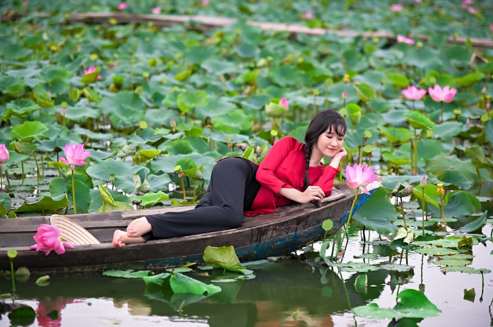 woman in red long sleeve shirt sitting on brown boat during daytime