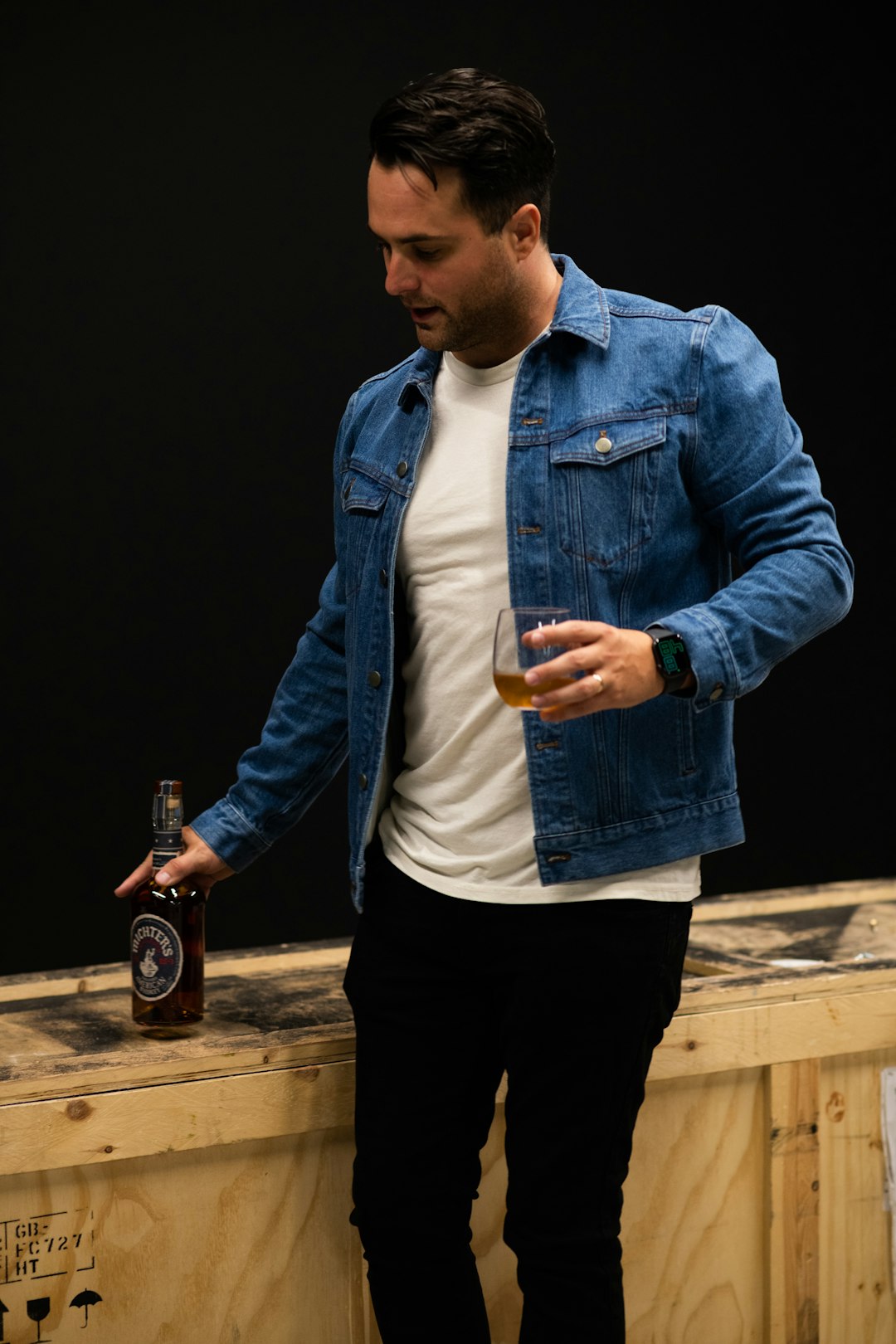 man in blue denim jacket holding bottle