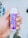 A hand holds a small cylindrical container with a purple label that reads 'Xylitol' and 'Rasa Bubblemint'. The background shows rows of shelves, indicating a store setting.